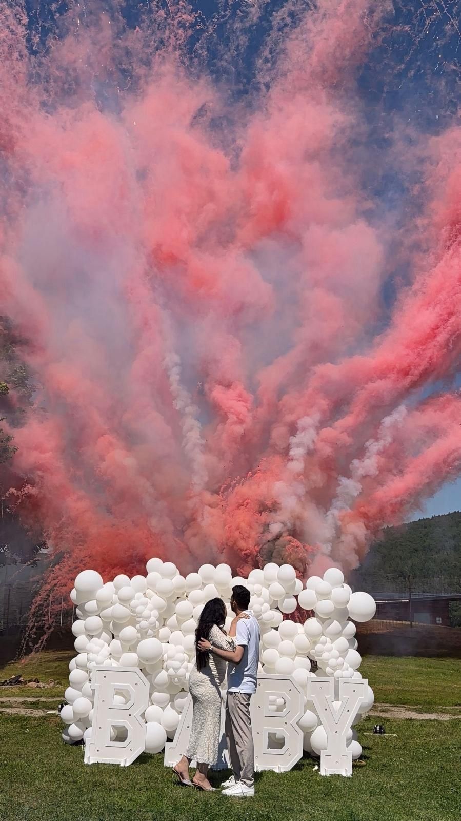 Gender Reveal mit rosa Rauch über dem Schriftzug BABY